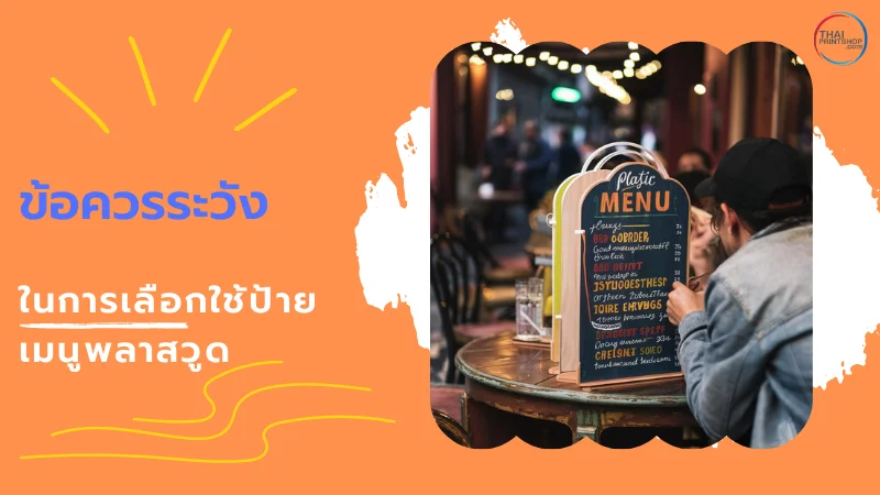 10 เหตุผลที่ทำให้ "ป้ายเมนูพลาสวูด" เป็นตัวเลือกที่ดีที่สุดสำหรับร้านอาหารและคาเฟ่ - Thaiprintshop ชายคนหนึ่งกำลังอ่านป้ายเมนูพลาสวูดที่วางอยู่บนโต๊ะในร้านอาหารกลางแจ้ง